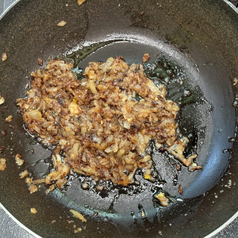 手順 4: 玉ねぎを加え軽く飴色に色づいてきたらおろしにんにく・生姜を加え炒める。