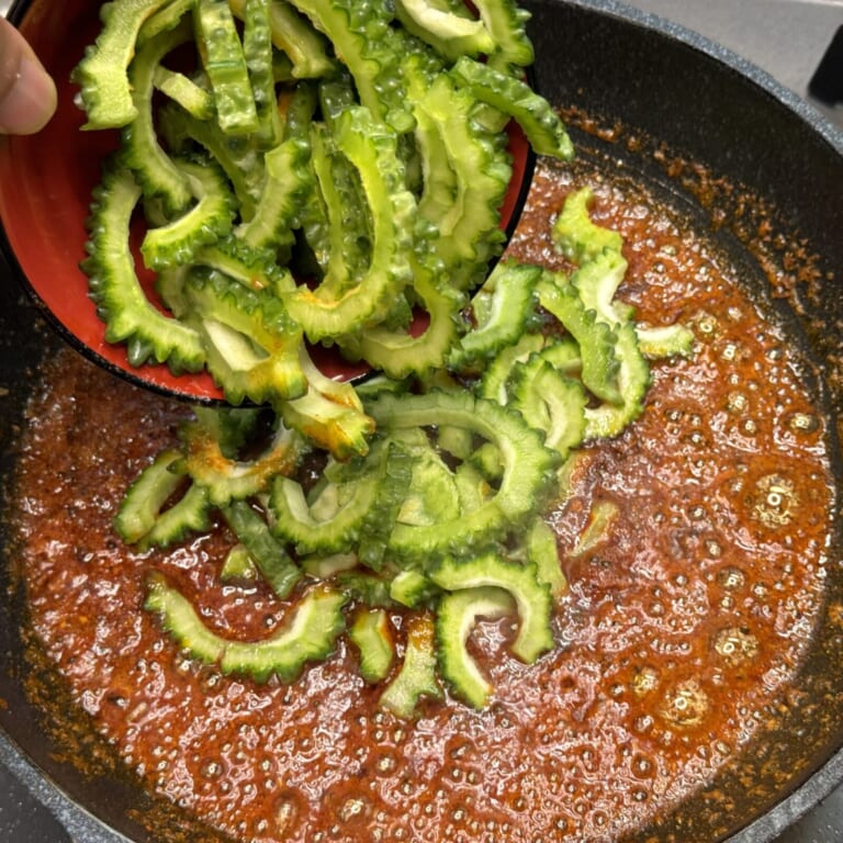 手順 2: 火を止めおろしにんにく、生姜を加え軽く火を通し、スパイスB、塩、黒糖を加えゴーヤを加え一緒に炒める。