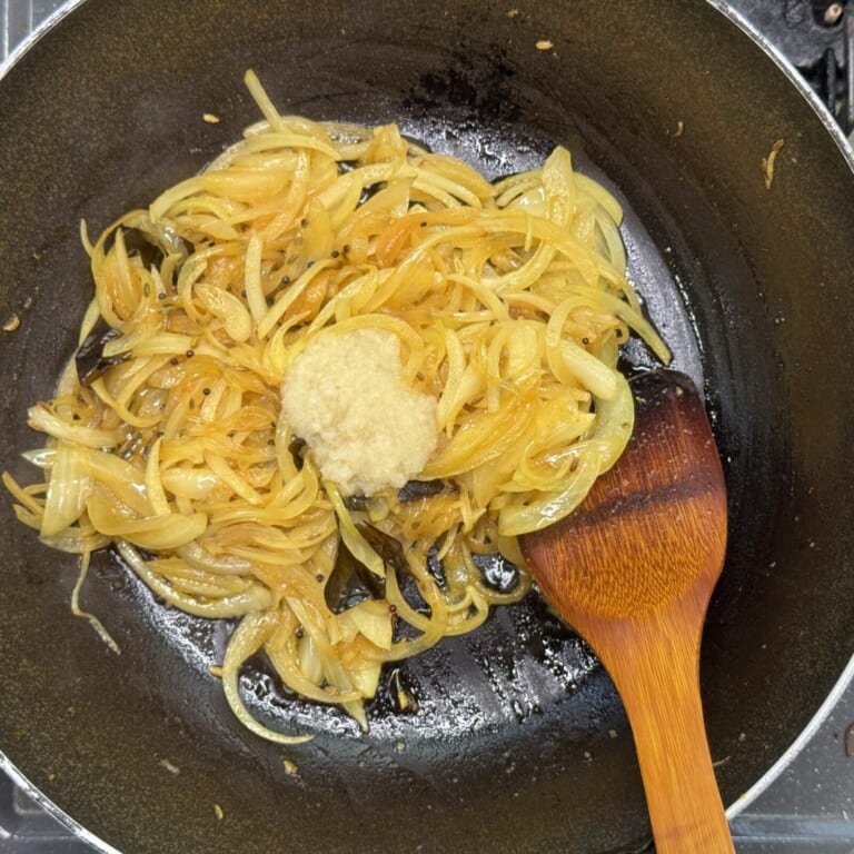 手順 3: 同じフライパンに玉ねぎを加え透明になるぐらい炒めたらおろしニンニク・生姜を加え炒める。