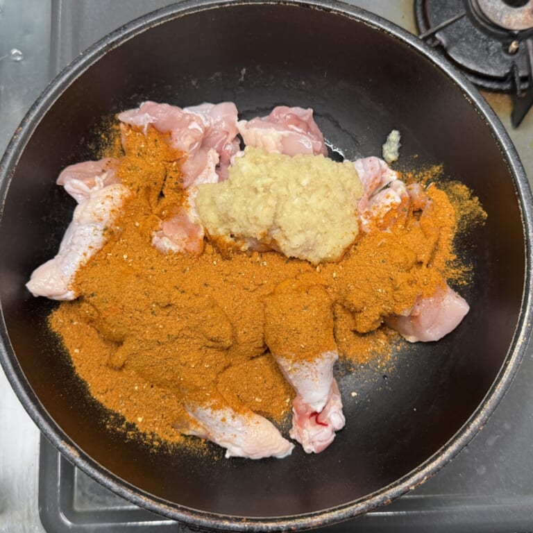 手順 1: フライパンに鶏もも肉、おろしニンニク。生姜、スパイスAを加え炒め合わせる。水を加えグツグツしてきたら弱火にして鶏もも肉に