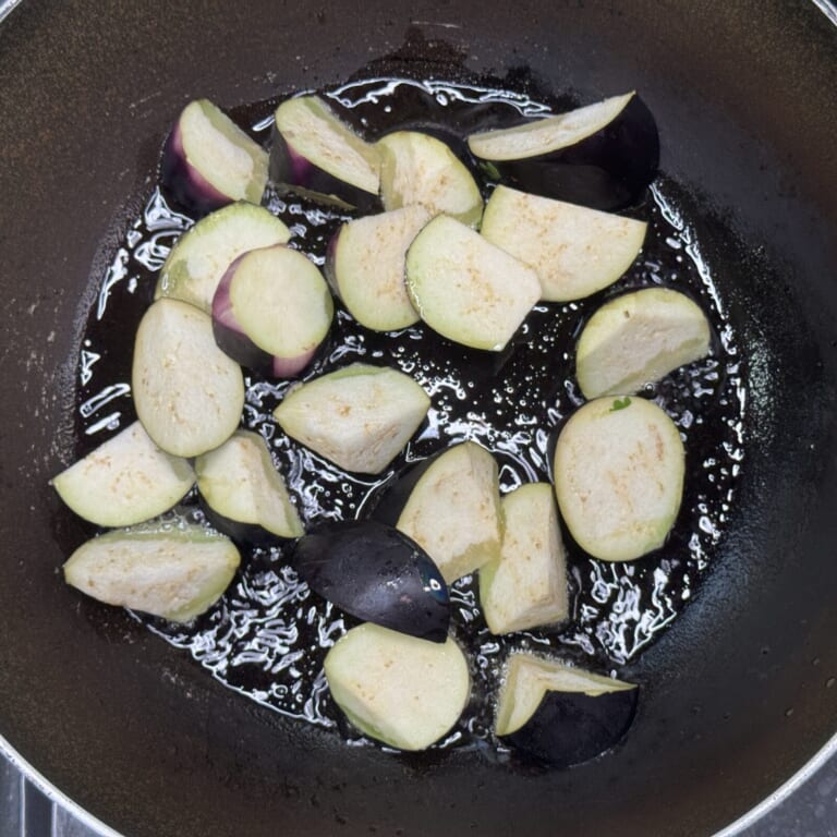 手順 2: 温めたフライパンに油をひきナスを炒める。