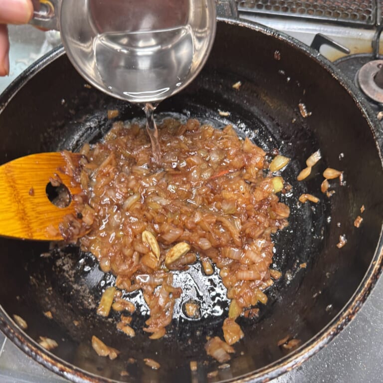 手順 3: 温めたフライパンに油を熱しスパイスAを加え香りが立ってきたら玉ねぎを加え飴色になるまで炒める。（水（分量外））を少しずつ