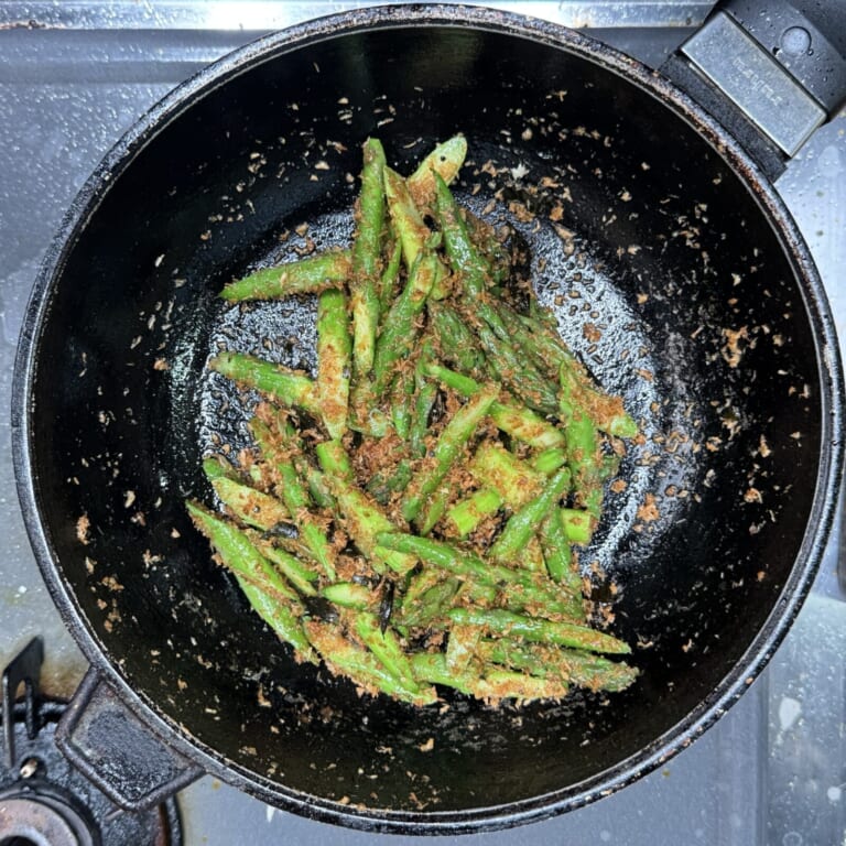 手順 3: ココナッツファインを加え炒め合わせ、薄茶色になったら茹でたアスパラガスと塩を炒め合わせる。