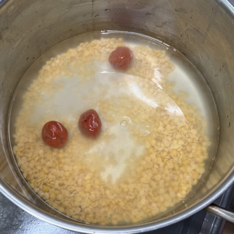 手順 3: ⒉の豆の水を切り鍋に入れ、水と梅干しを加え煮込み始める。