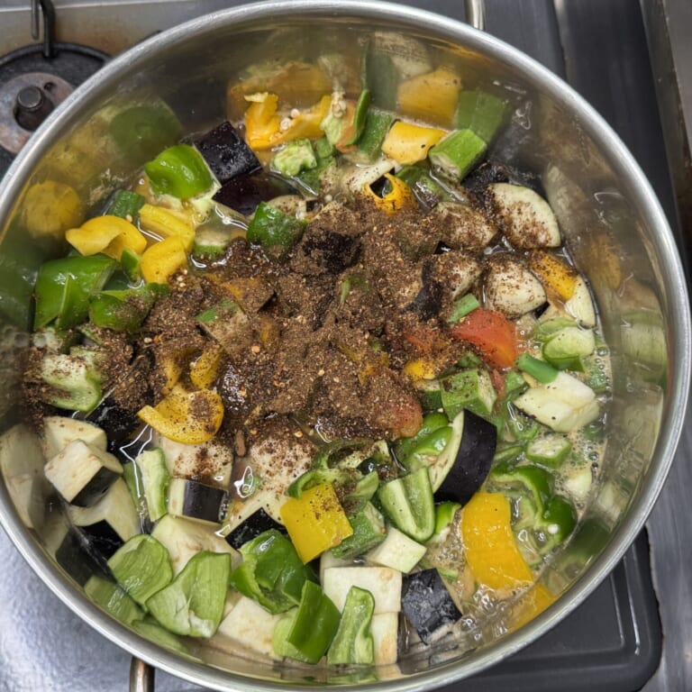 手順 4: 野菜を火が通りにくいものから順々にすべて入れて、スパイスAを大さじ2を加える。弱火にして豆と野菜に火が通るまで煮込む。(