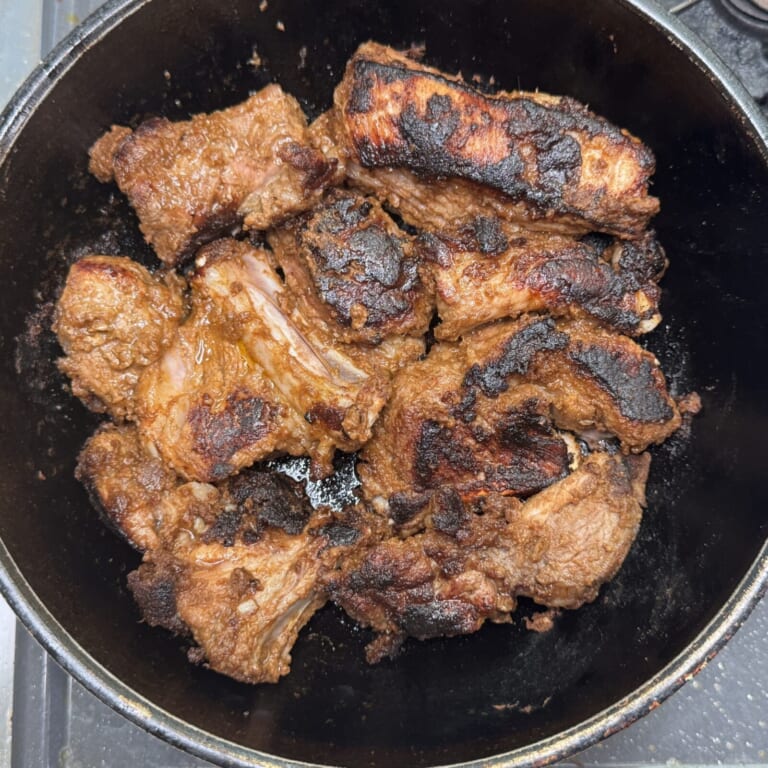 手順 2: 温めたフライパンで油を熱しマリネしておいたスペアリブをマリネ液ごと表面に焼き目をつけるように焼き取り出しておく。