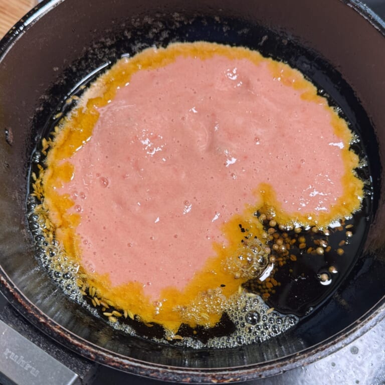 手順 4: 温めたフライパンに油（マスタードオイル）を熱しスパイスBを熱する。パチパチしてきたら玉ねぎ（ペースト）とトマト（ペースト