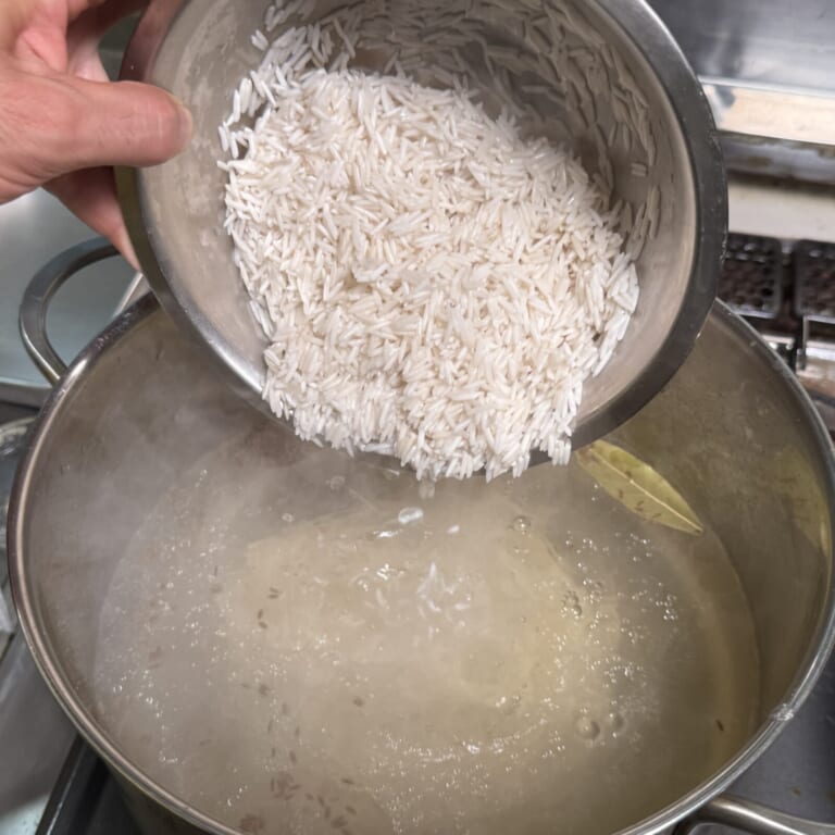手順 4: 鍋に（コメを茹でる用）の材料とスパイスAを入れ沸騰させ、バスマティを7分茹でる。