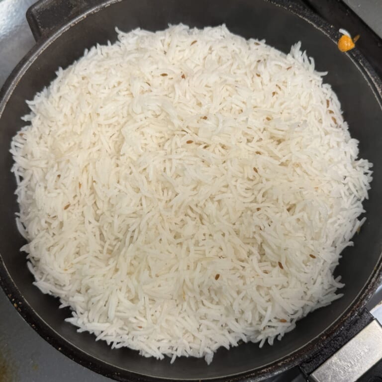 手順 6: バスマティライスが茹で上がったらザルにあげ、敷き詰めておいた鶏肉の上に被せる様にのせていく。