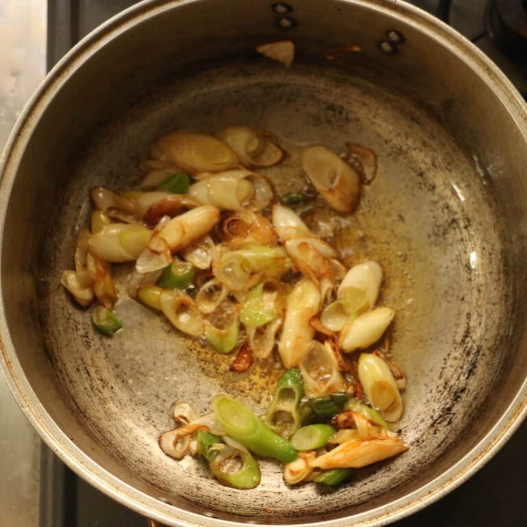 手順 2: 温めたフライパンでごま油を熱し、ざくぎりにした長ねぎを加えます。